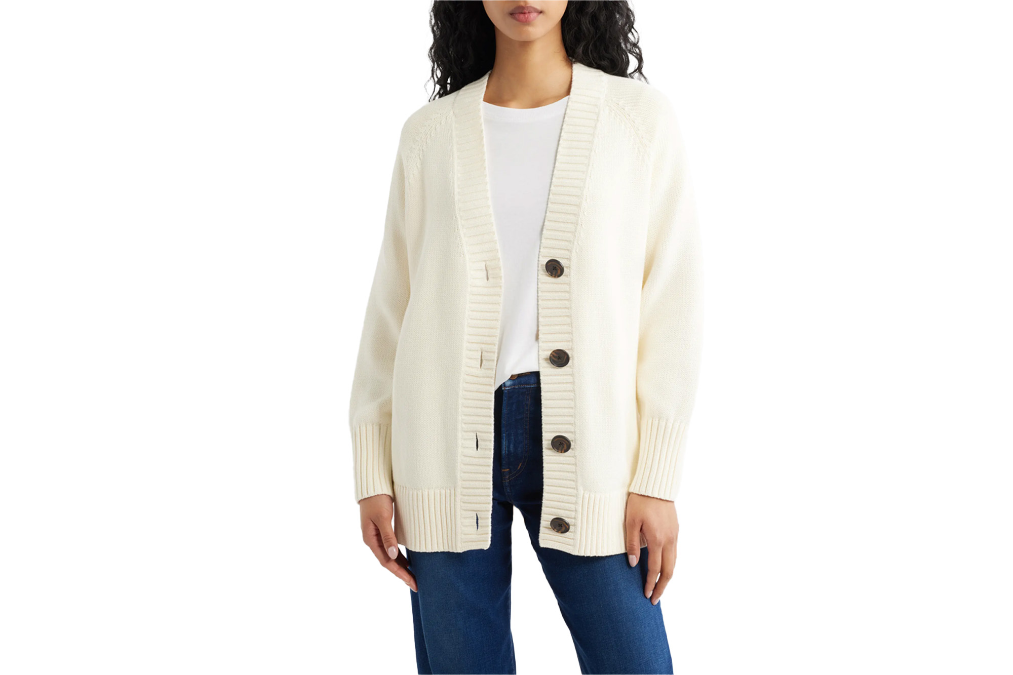 A person wearing a cream-colored button-up cardigan over a white t-shirt and blue jeans.