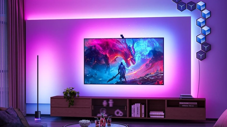 A TV with colorful ambient backlighting in a dark room.