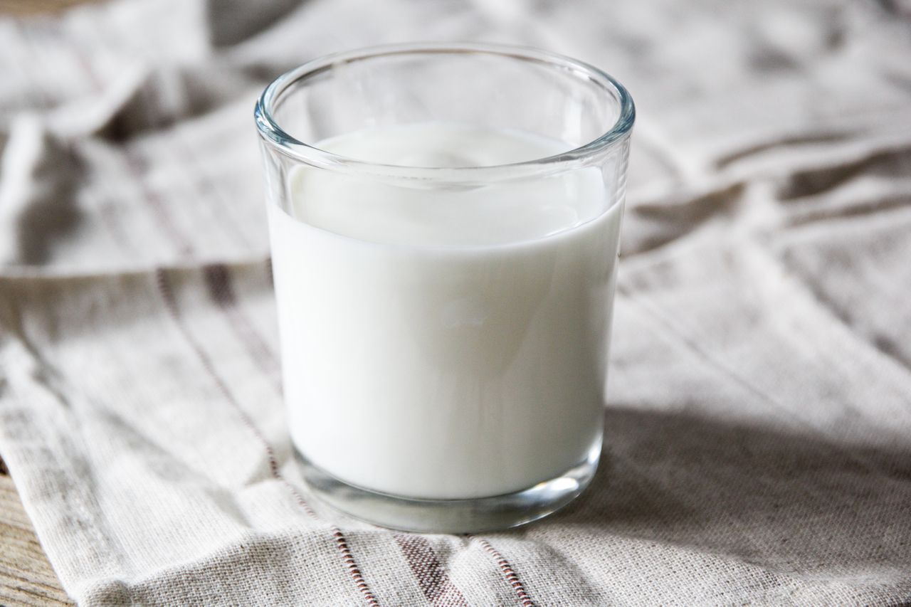 A clear glass filled with milk on a cloth surface