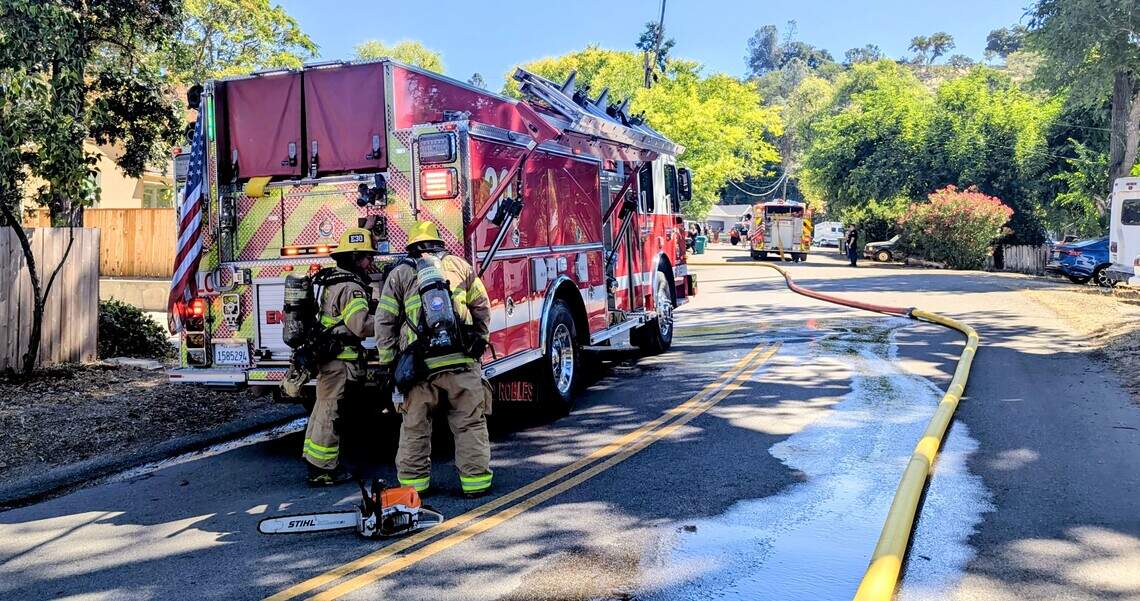 Fire engines and hose lines fill Robles Avenue as crews respond to an attic fire at a nearby apartment complex in Atascadero on Tuesday, July 21, 2026.