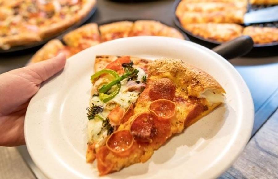Two slices of different types of Pizza Ranch pizza are shown near the restaurant’s buffet. | Courtesy Pizza Ranch