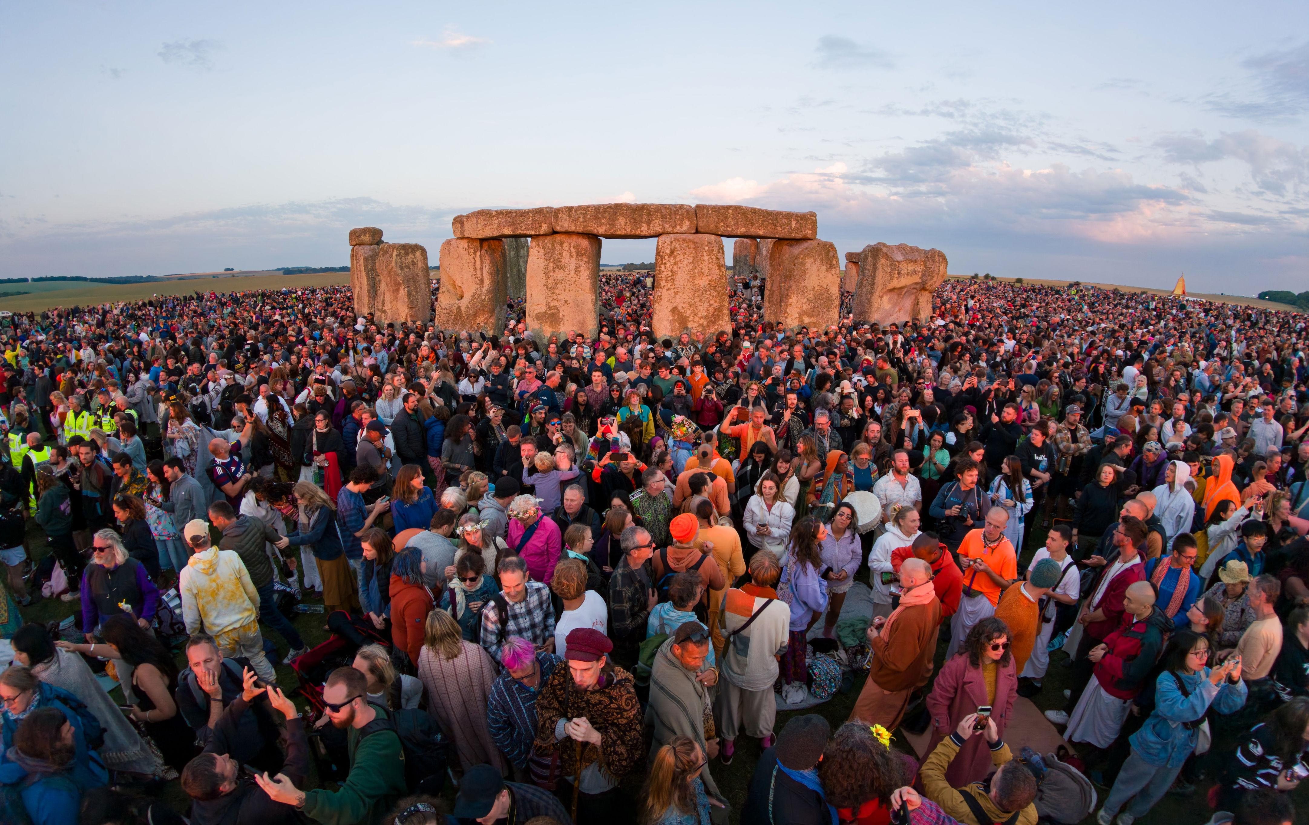 Crowd gathers around Stonehenge during a festive event, capturing the historical site's atmosphere and social gathering for a travel article