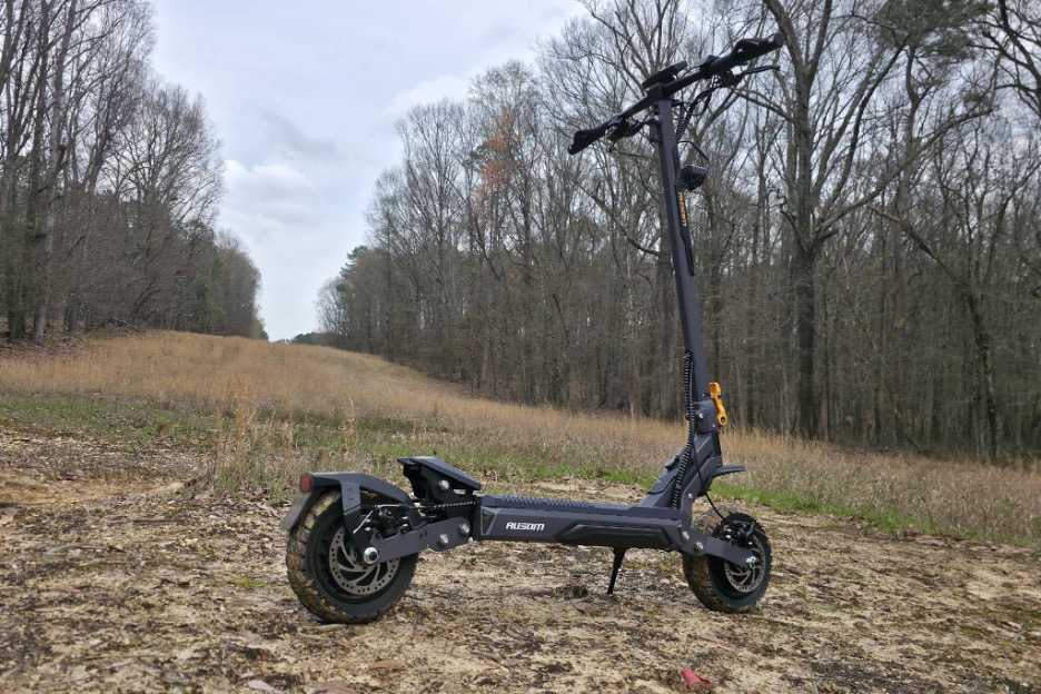 Ausom electric scooter with dirt on the tires in a forrest surrounded by trees.