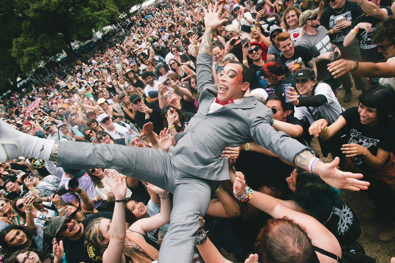 A performer in a suit crowdsurfing over an audience