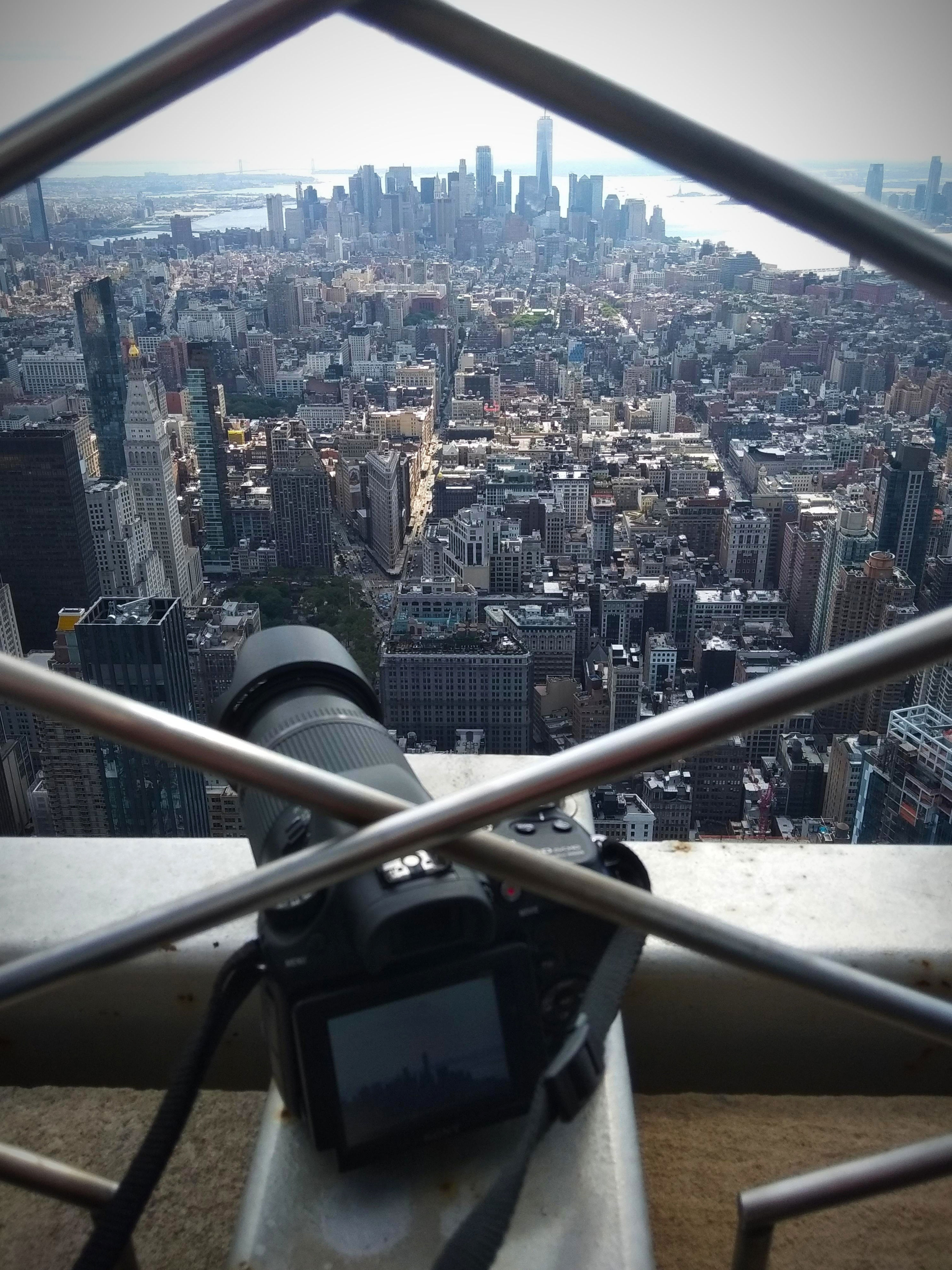 Camera on ledge capturing a cityscape view from a high vantage point, featuring sprawling urban landscape and distant skyline