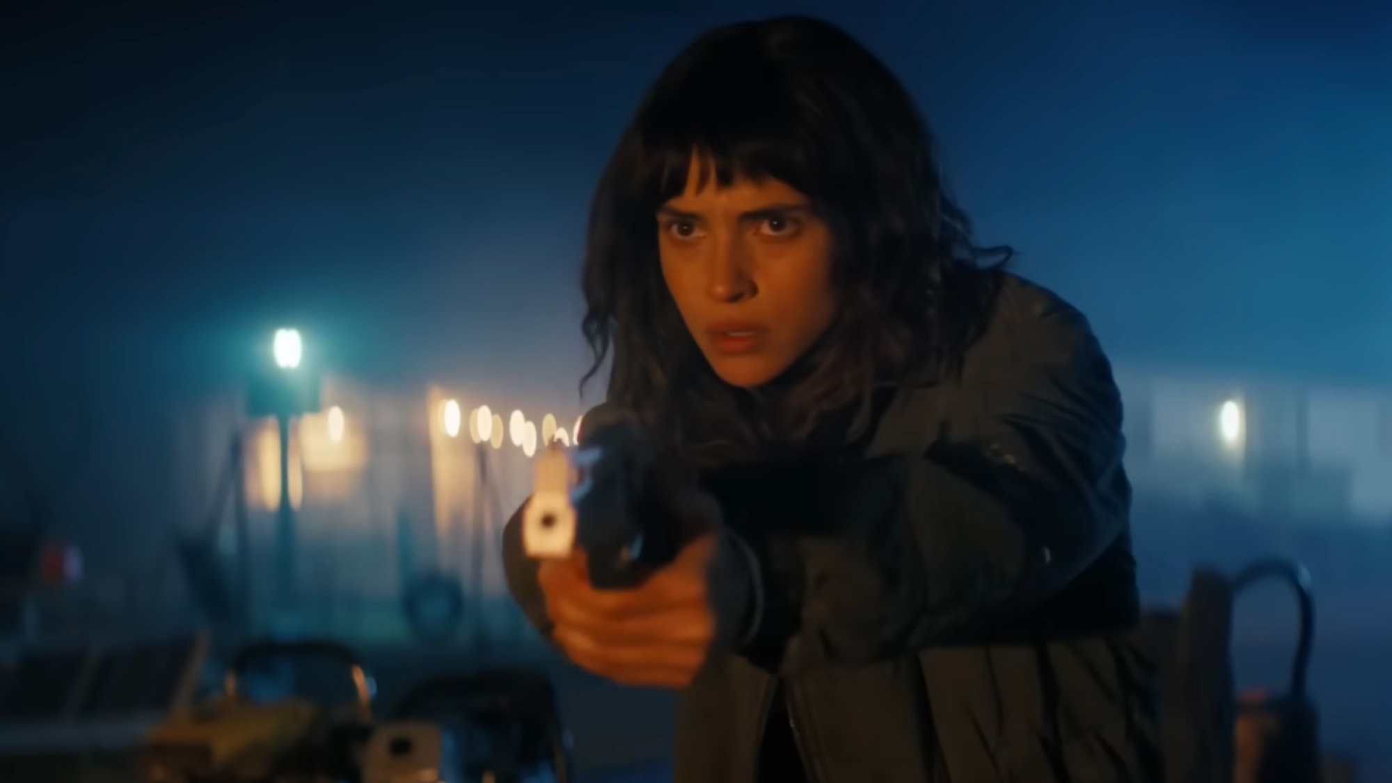 Adria Arjona holding a gun and looking very serious in Onslaught