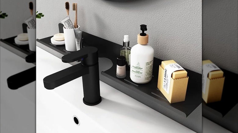 A narrow wall-mounted shelf installed on the wall behind a bathroom sink and used to store toiletries.
