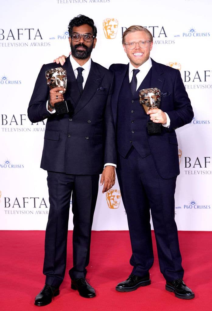Romesh Ranganathan and Rob Beckett holding awards, smiling on red carpet at BAFTA Television Awards.