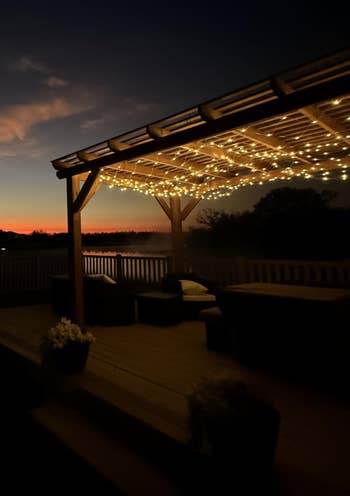 A cozy outdoor patio with string lights under a pergola, overlooking a sunset. Perfect for evening relaxation and entertaining