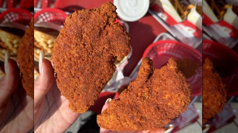 Hands holding two chicken tenders at Chicken Guy!