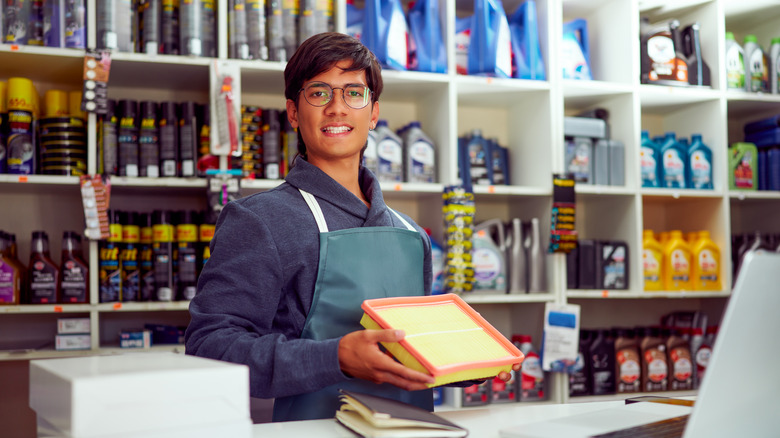 An employee at a car parts store holding an engine air filter