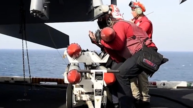 An Aviation Ordnanceman loads a missile onto an F-35B Lightning II onboard an aircraft carrier.