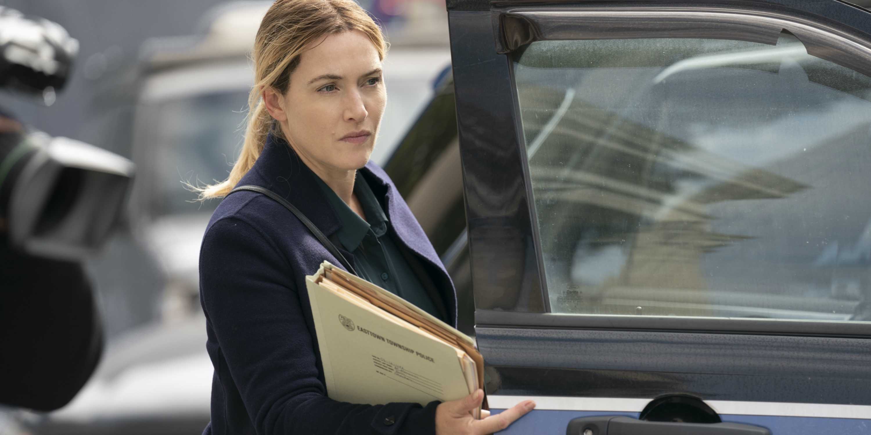 Mare Sheehan (Kate Winslet) with files outside a police car in Mare of Easttown