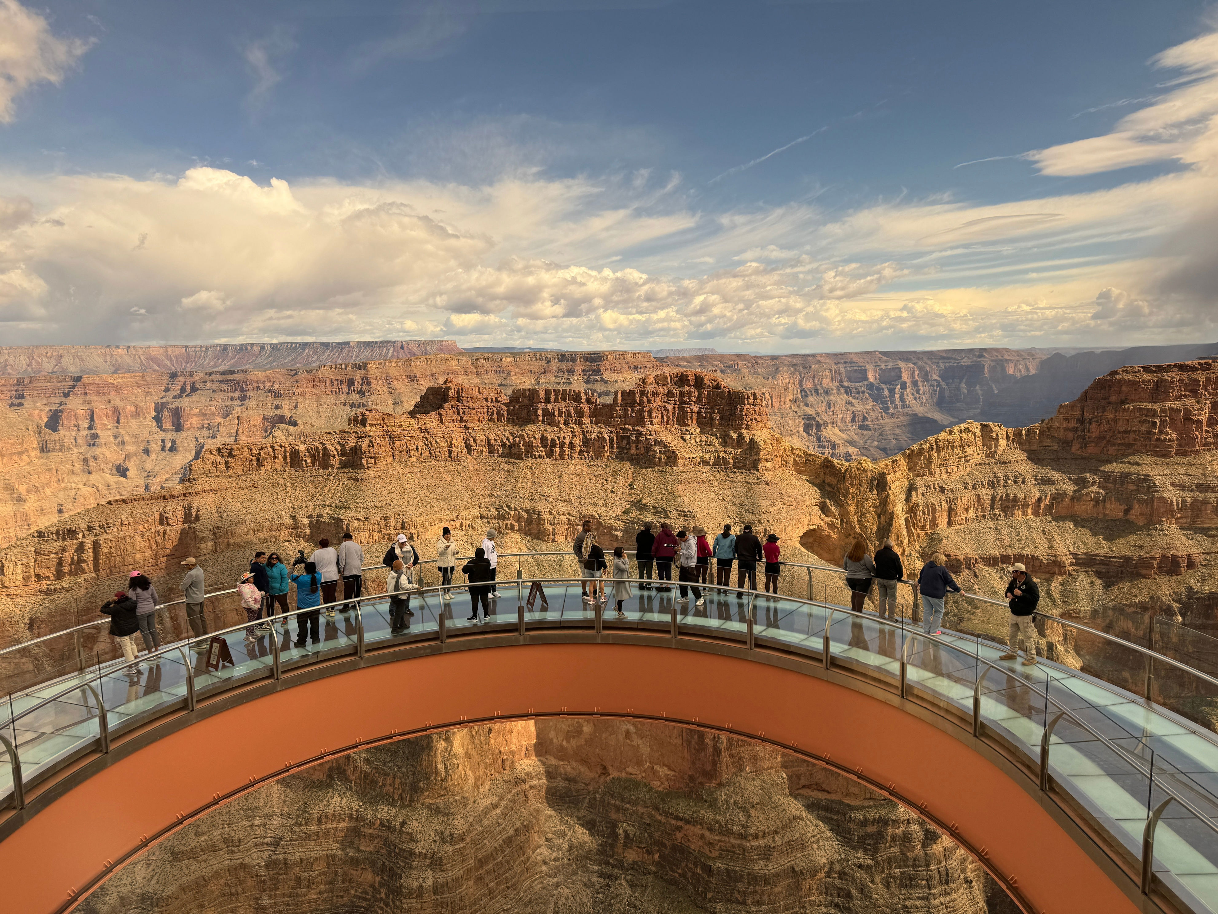 People walking on the Grand Canyon Skywalk, a transparent horseshoe-shaped bridge over the canyon offering panoramic views