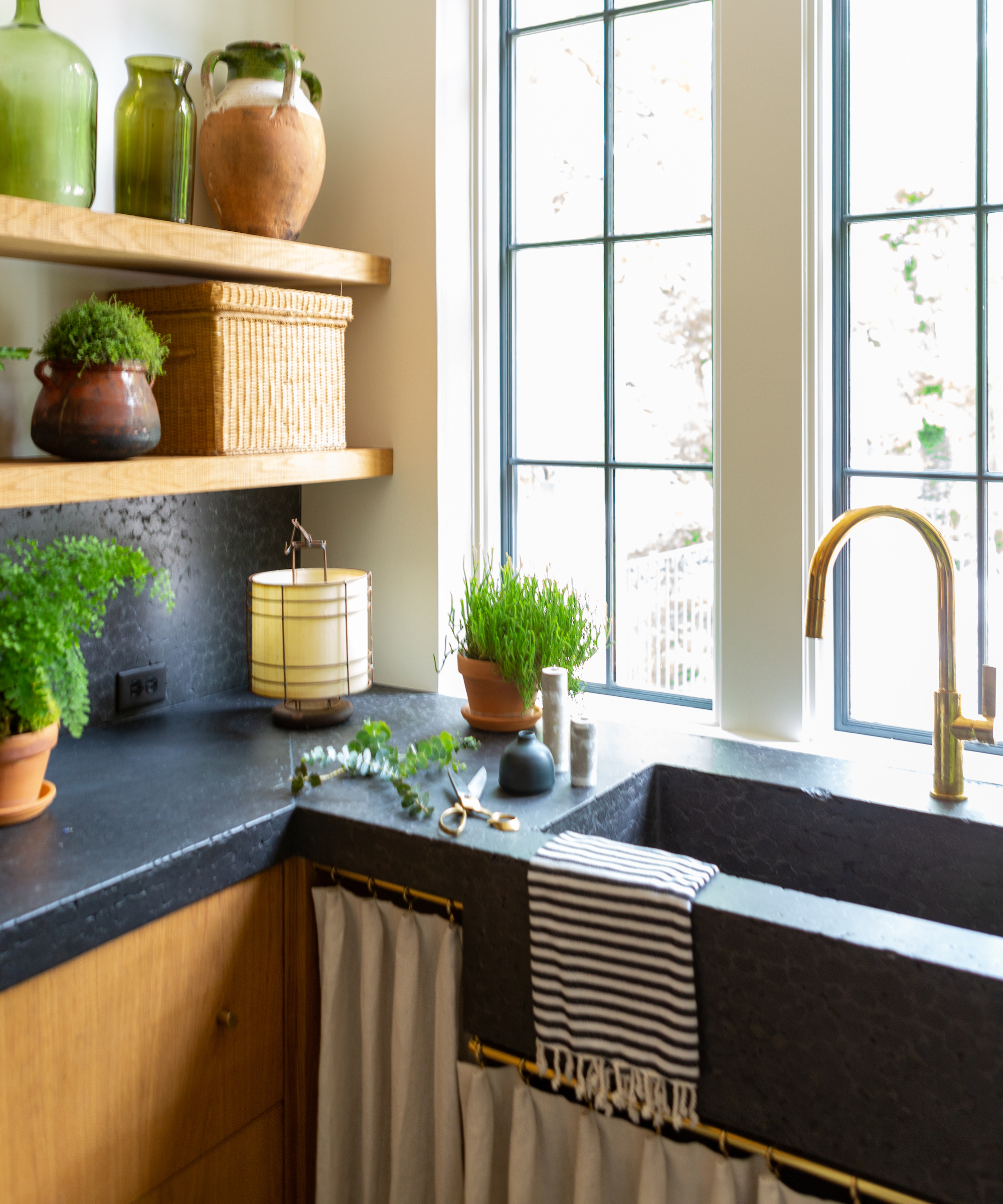 black stone sink carved with curtain cupboards and brass tap