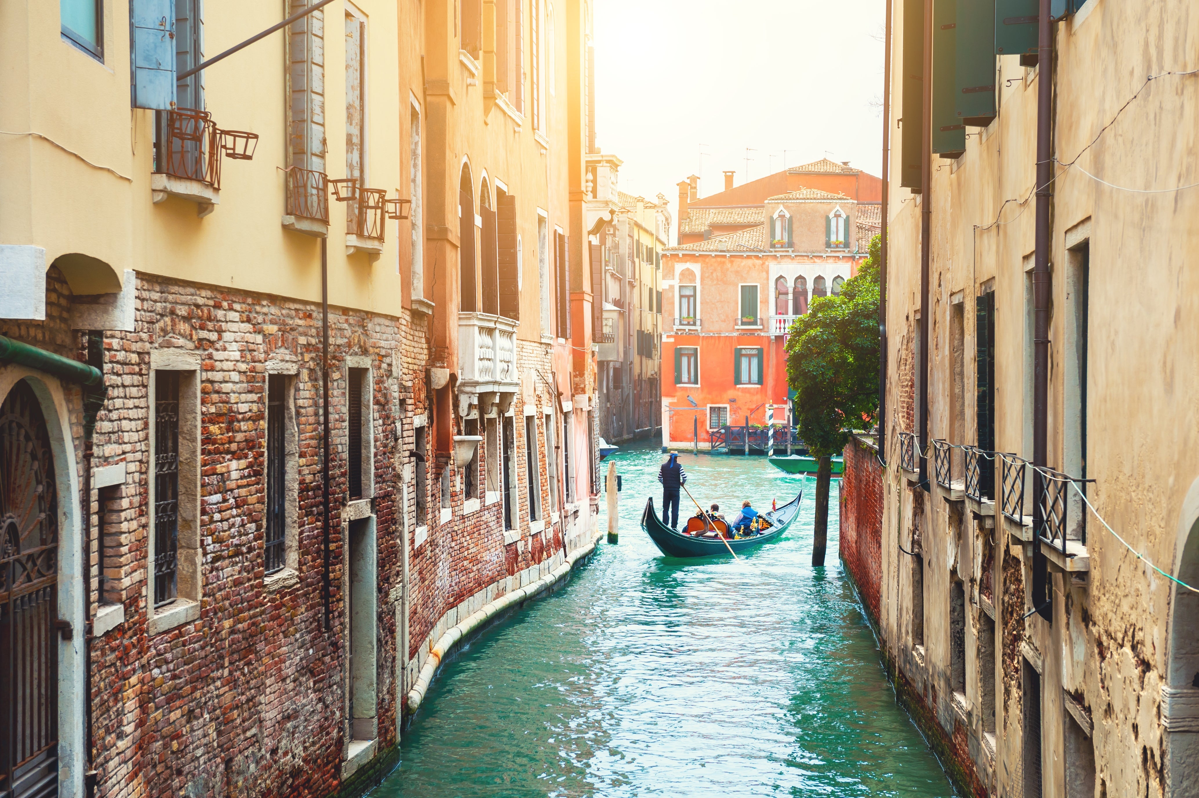 A gondola navigates a narrow canal flanked by old, charming buildings in Venice, Italy, under soft daylight, showcasing classic Venetian architecture