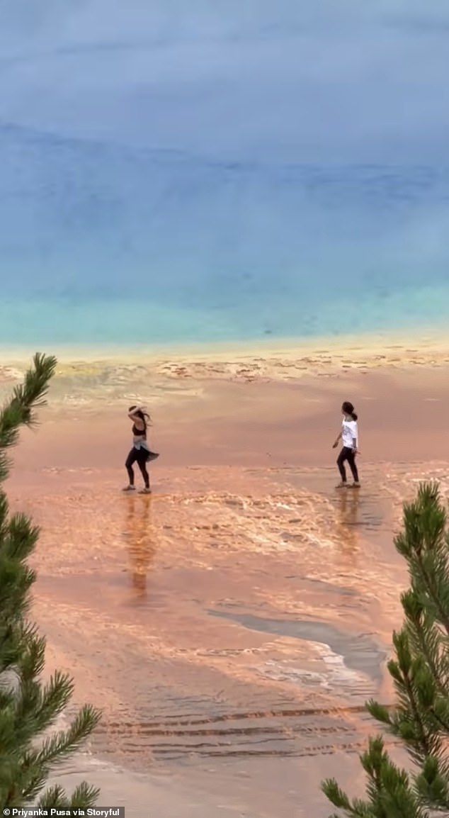 The two women were pictured on the spring's microbial mats, which the National Park Service has warned can be just like 'a thin crust with super-heated water below'
