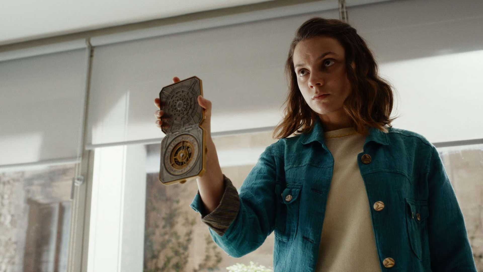 Lyra holds up the golden compass in His Dark Materials.