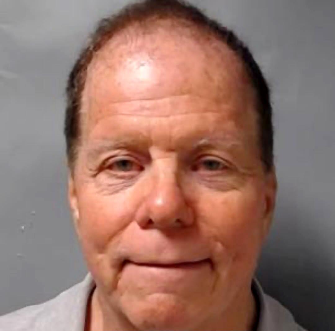 Mugshot of a slightly smiling man with thinning hair.