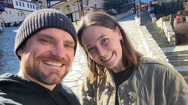 Konrad Warzecha and his partner Caro smile for a selfie on an old stone street in Skopje, North Macedonia.