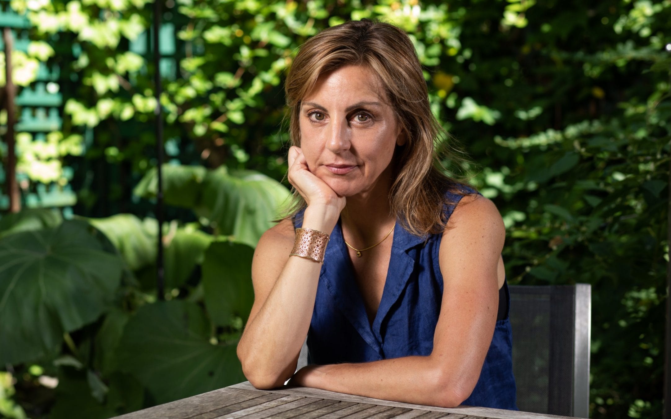 Carole Hooven sitting at an outdoor table resting her head on one of her hands