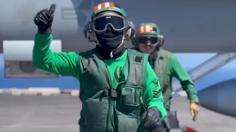 Aviation Boatswain's Mates running from an aircraft following recovery operations aboard an aircraft carrier
