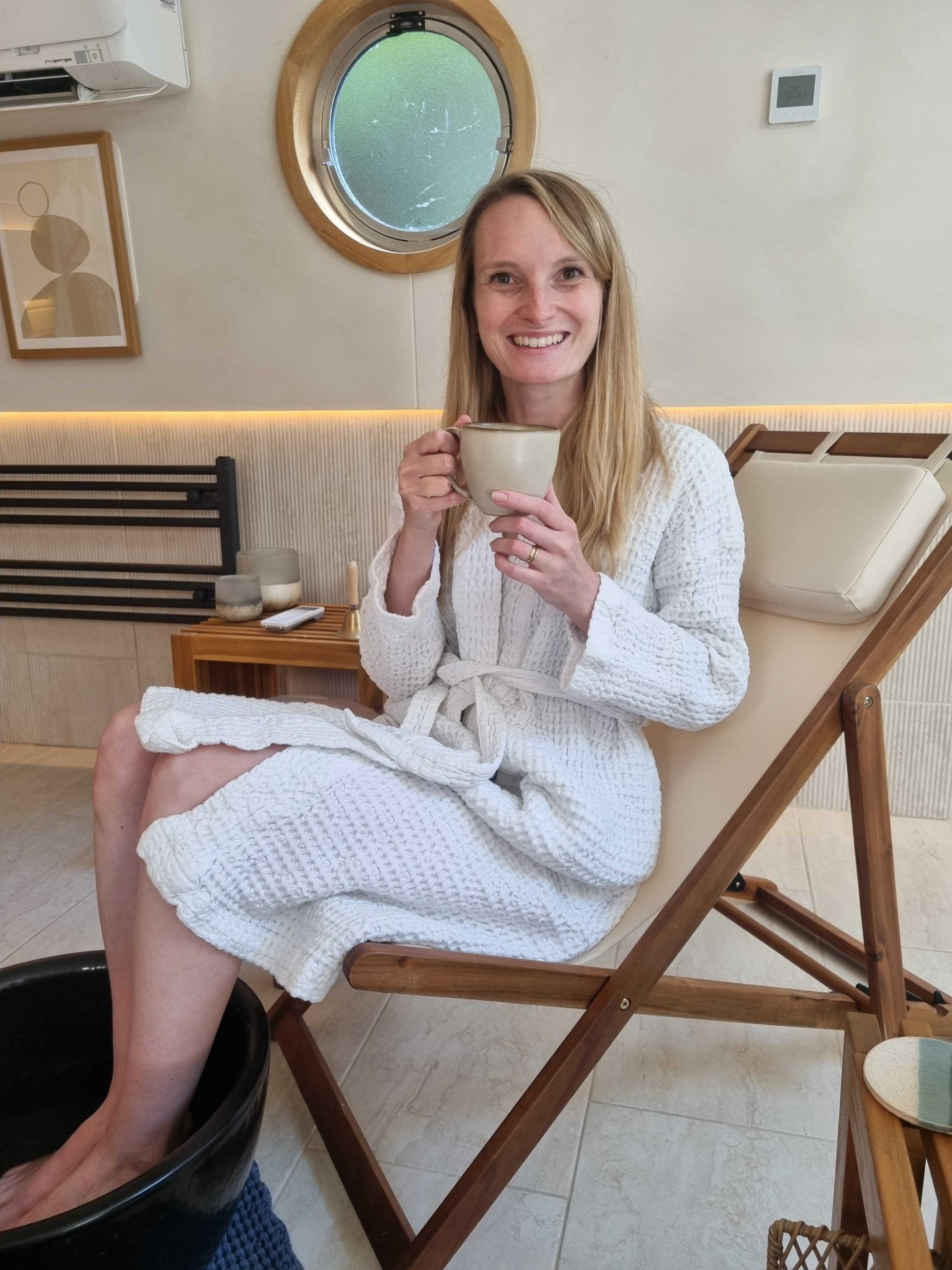 Rachel Moss, Metro's Lifestyle Editor, smiling with a cup of herbal tea in a robe on the spa boat