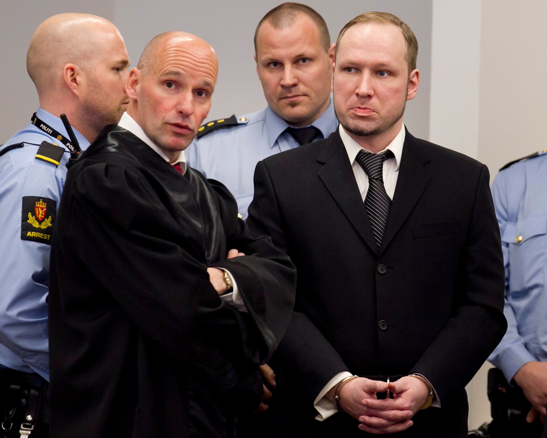 Defendant Anders Behring Breivik with his lawyer Geir Lippestad, left, during the third day of proceedings in courtroom. There are police men behind them.