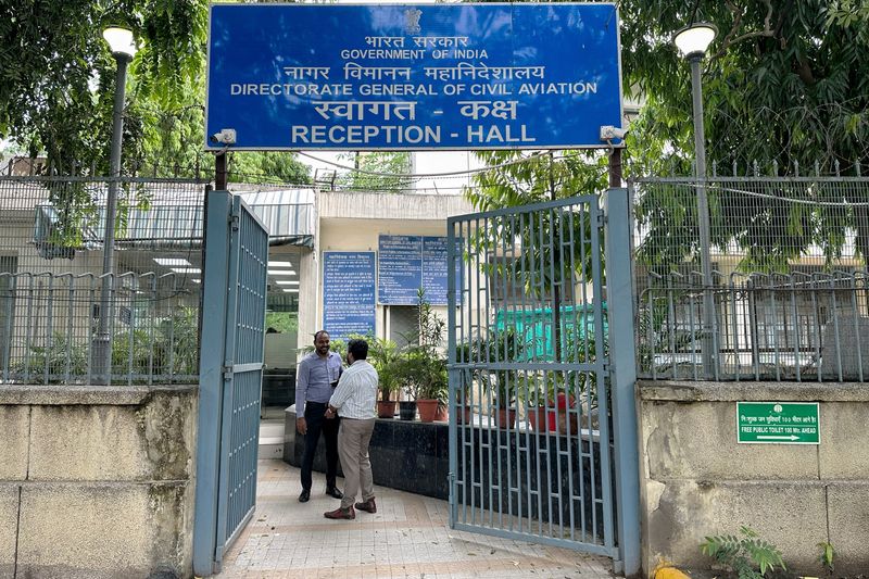People stand outside the entrance to the headquarters of the Directorate General of Civil Aviation in New Delhi