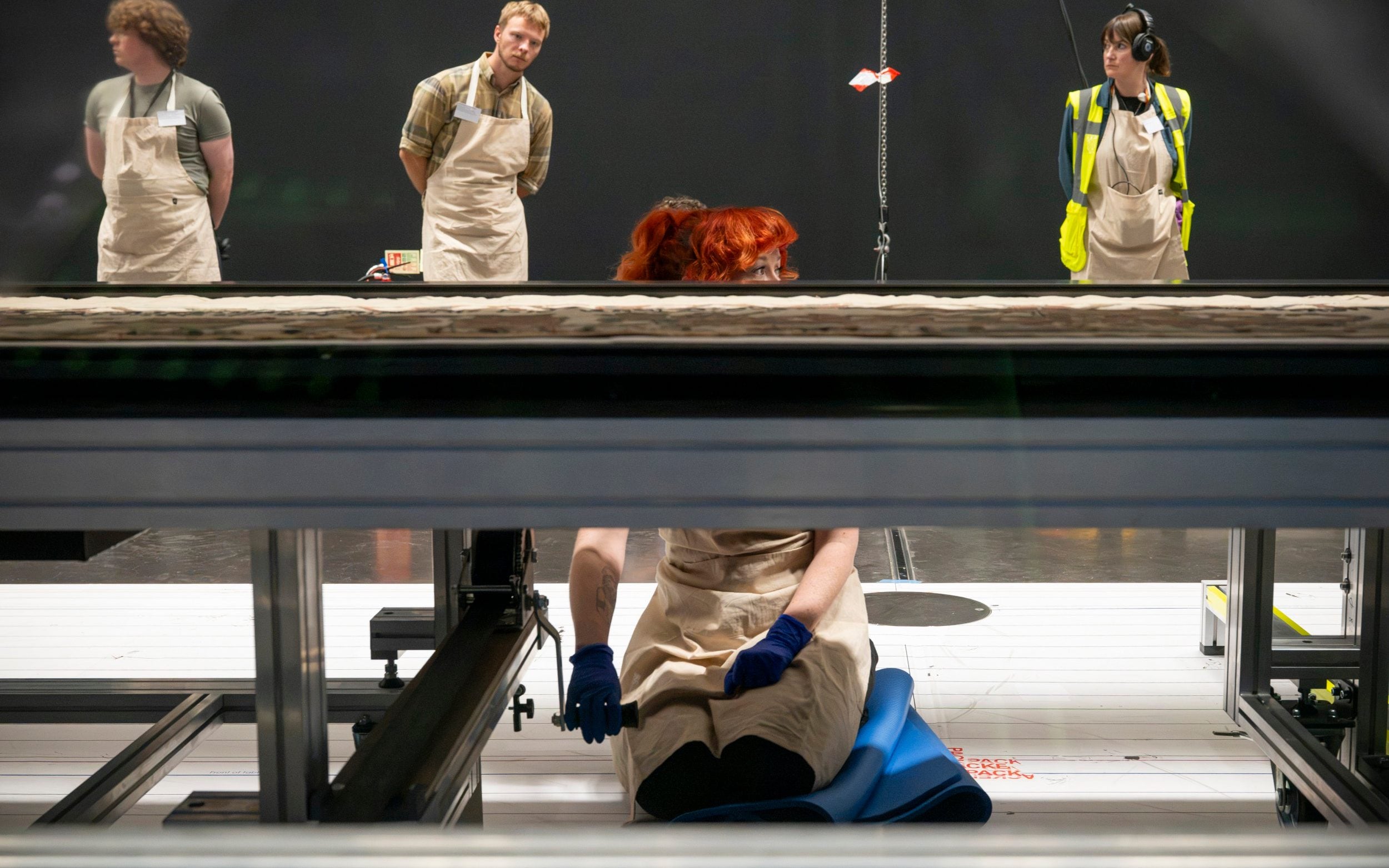Guardrails are erected; chocks are removed from the table's wheels and placed in purple trays; unfurled winches are connected to the case