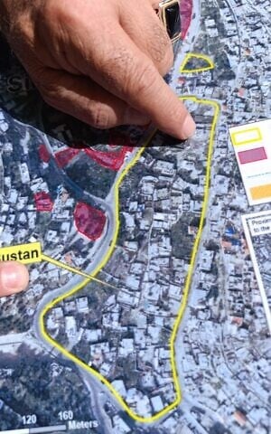 Angela Godfrey-Goldstein points to a map of the al-Bustan neighborhood of East Jerusalem, May 20, 2026 (Zev Stub/Times of Israel)