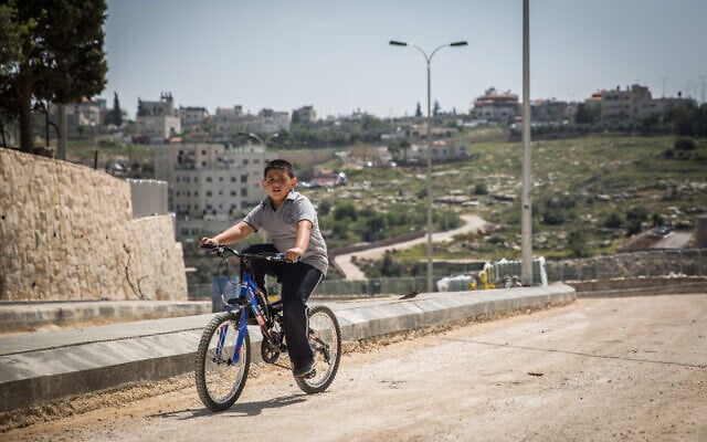 A young Palestinian boy rides a bicycle on a road being constructed in the East Jerusalem neighborhood of Shuafat, on March 30, 2016 (Hadas Parush/Flash90)