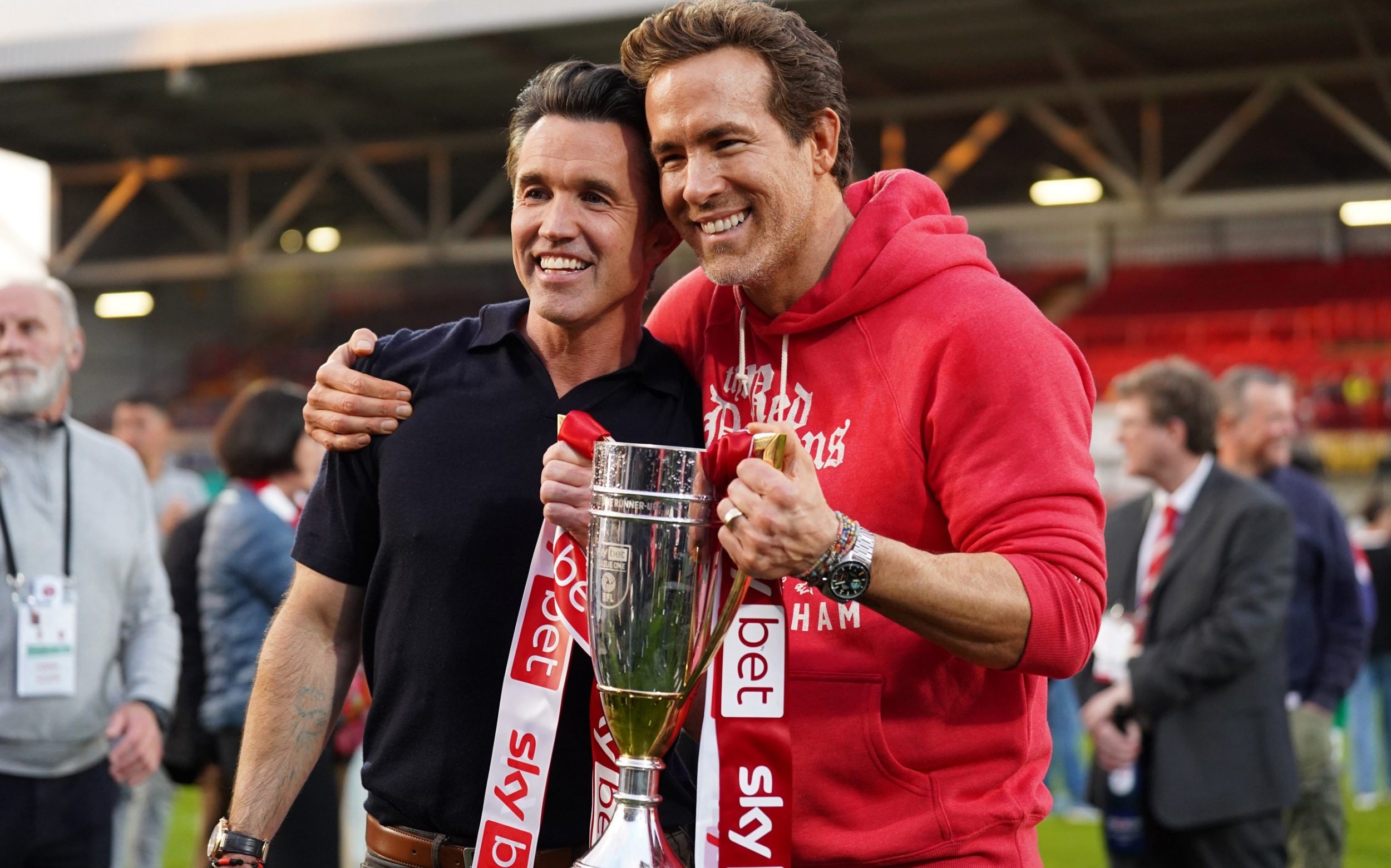 Rob McElhenney and Ryan Reynolds, co-owners of Wrexham AFC, pose for a photo with the trophy following the club's promotion to the Sky Bet Championship during the Sky Bet League One match between Wrexham AFC and Charlton Athletic FC at Racecourse Ground on April 26, 2025 in Wrexham, Wales.