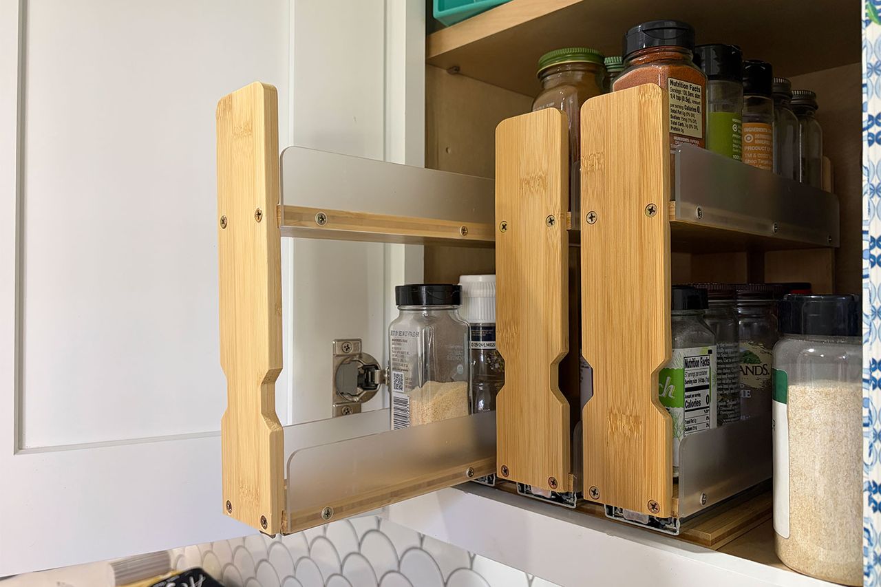 Bamboo spice rack installed in a cabinet holding several spice containers