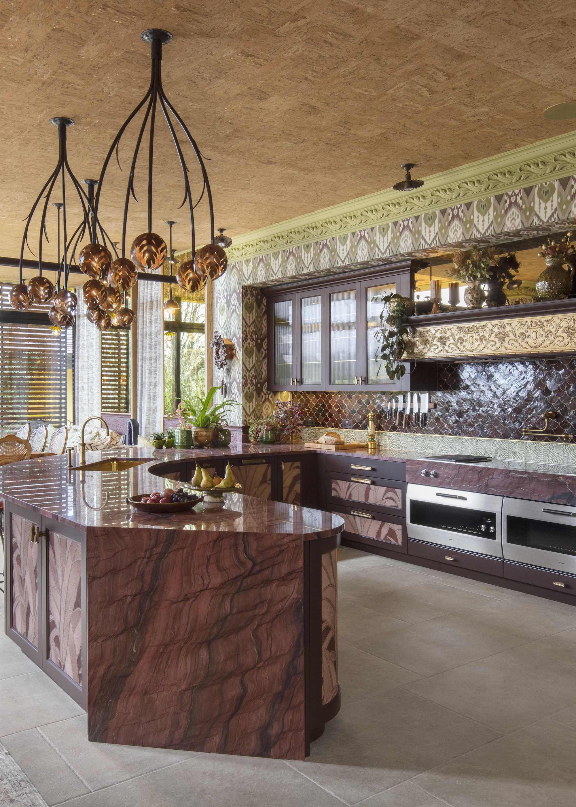 kitchen with wallpaper with orange ceiling, yellow coving, glossy brown tiled wall, with purple veined counter and kitchen island, large format grey floor tiles and double stove