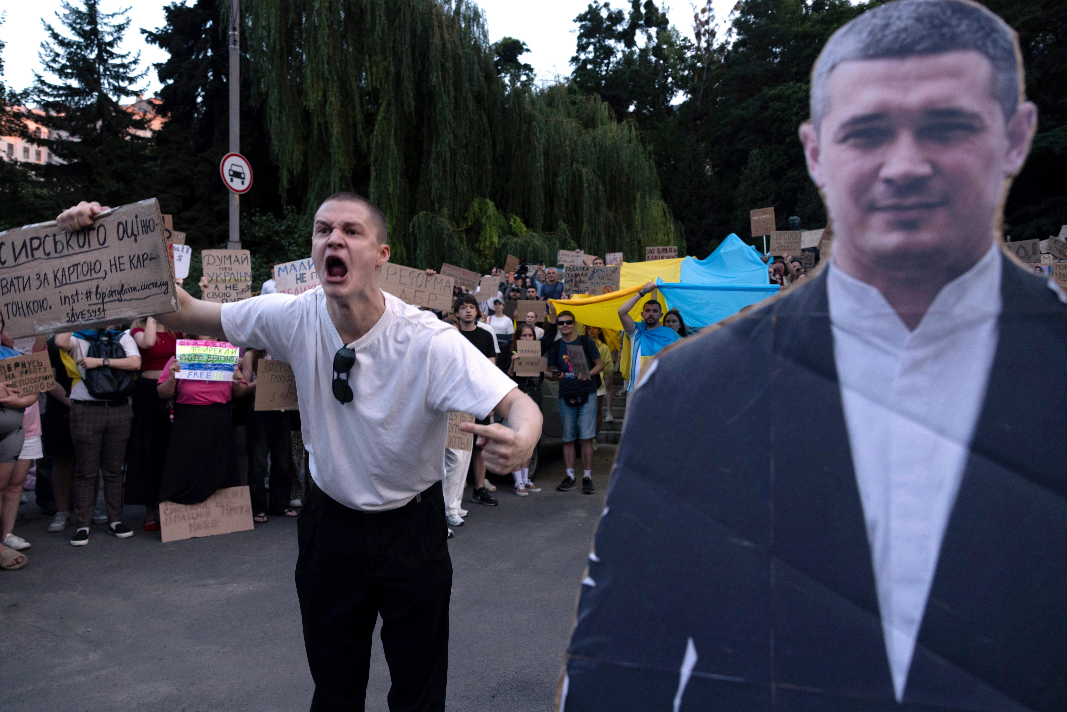 A man holds up a sign and yells in protest next to a cutout of Fedorov.