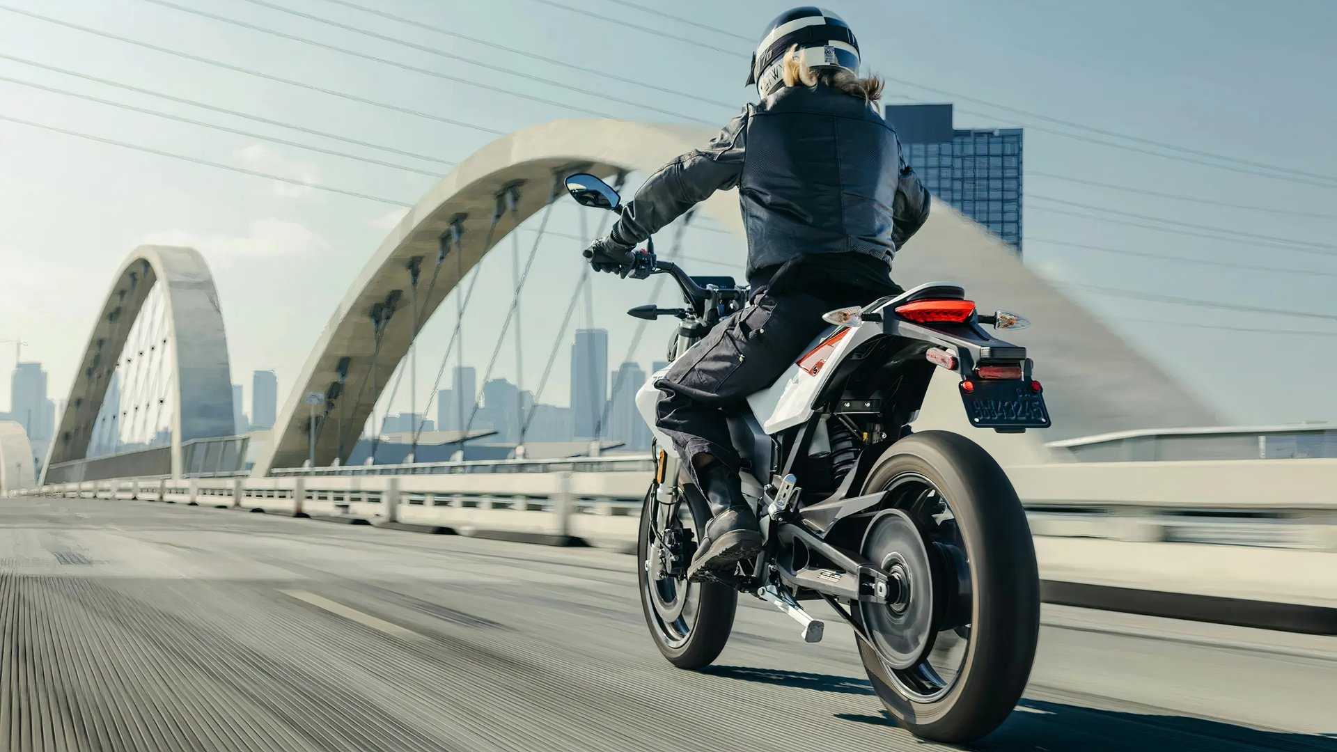 Zero FXE tracking shot of a rider on a bridge headed to a city