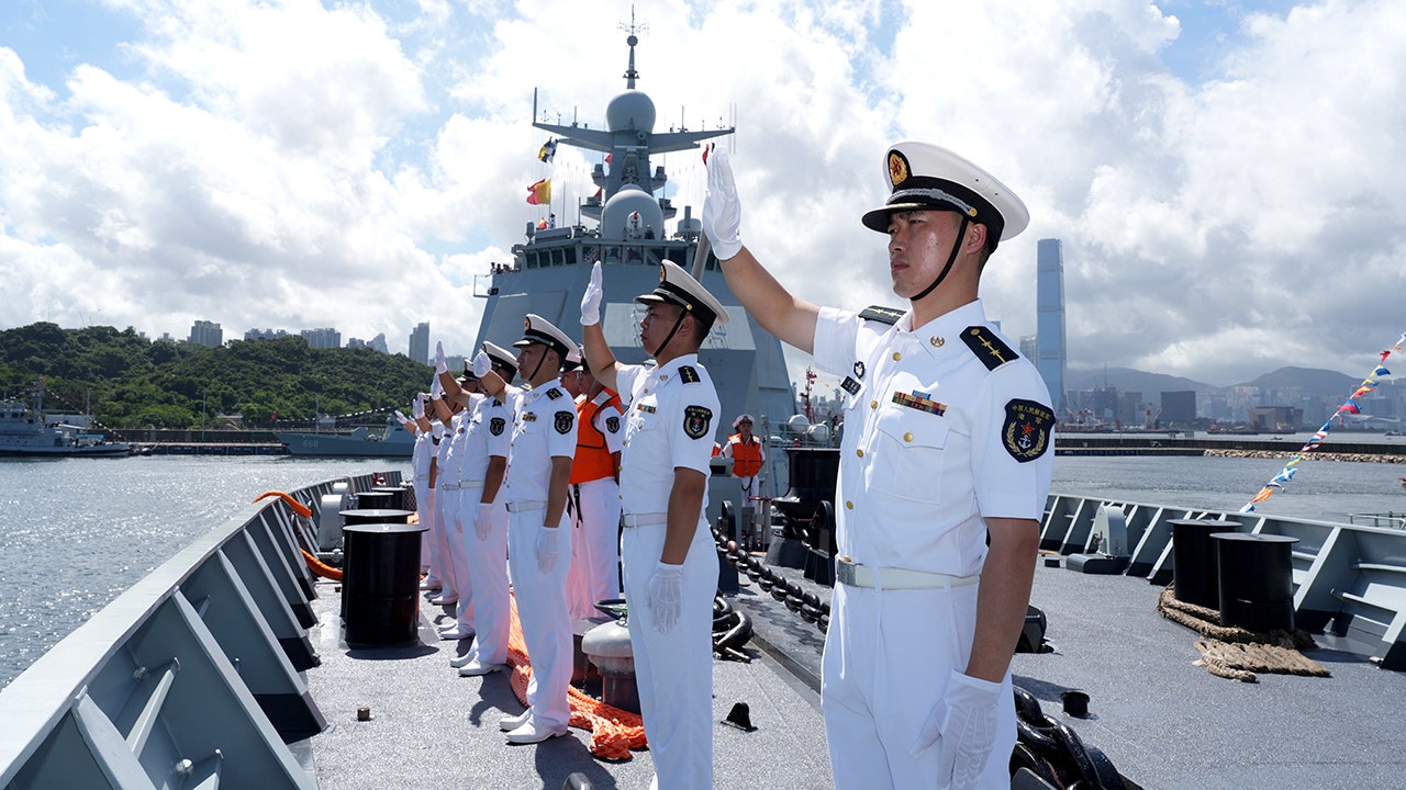 Officers and soldiers on the Chinese People's Liberation Army PLA Navy's guided-missile destroyer Nanning wave as the ship enters the waters of the Hong Kong Special Administrative Region in south China, July 2, 2026.