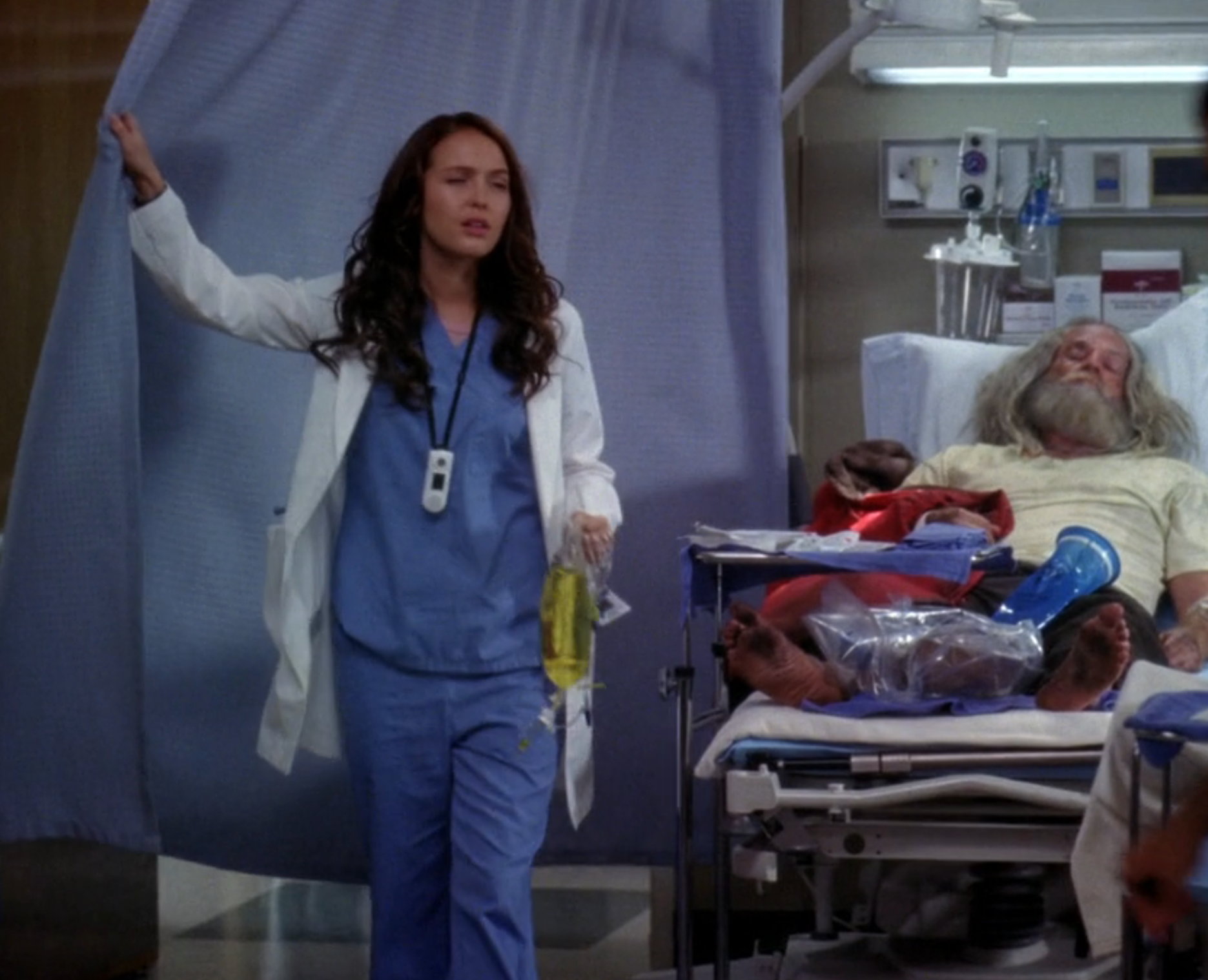 A hospital scene with a doctor in scrubs holding a chart, standing by a patient on a bed with feet in casts