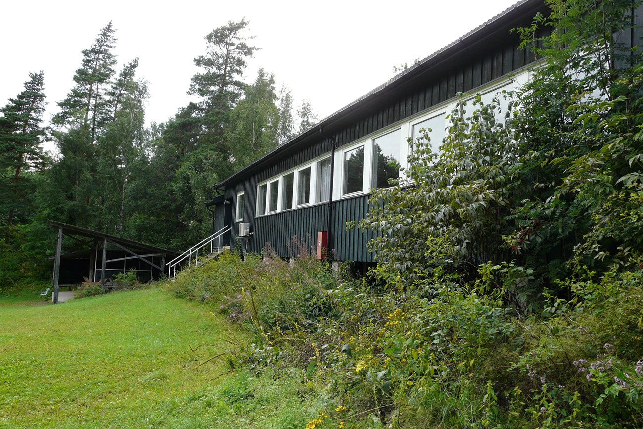 A green school building and woodland area on the camp grounds.