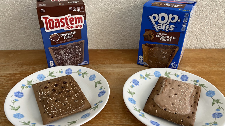 Toast'em Pop-Ups chocolate pastry and Pop-Tarts frosted chocolate fudge pastries on plates with respective boxes on countertop.