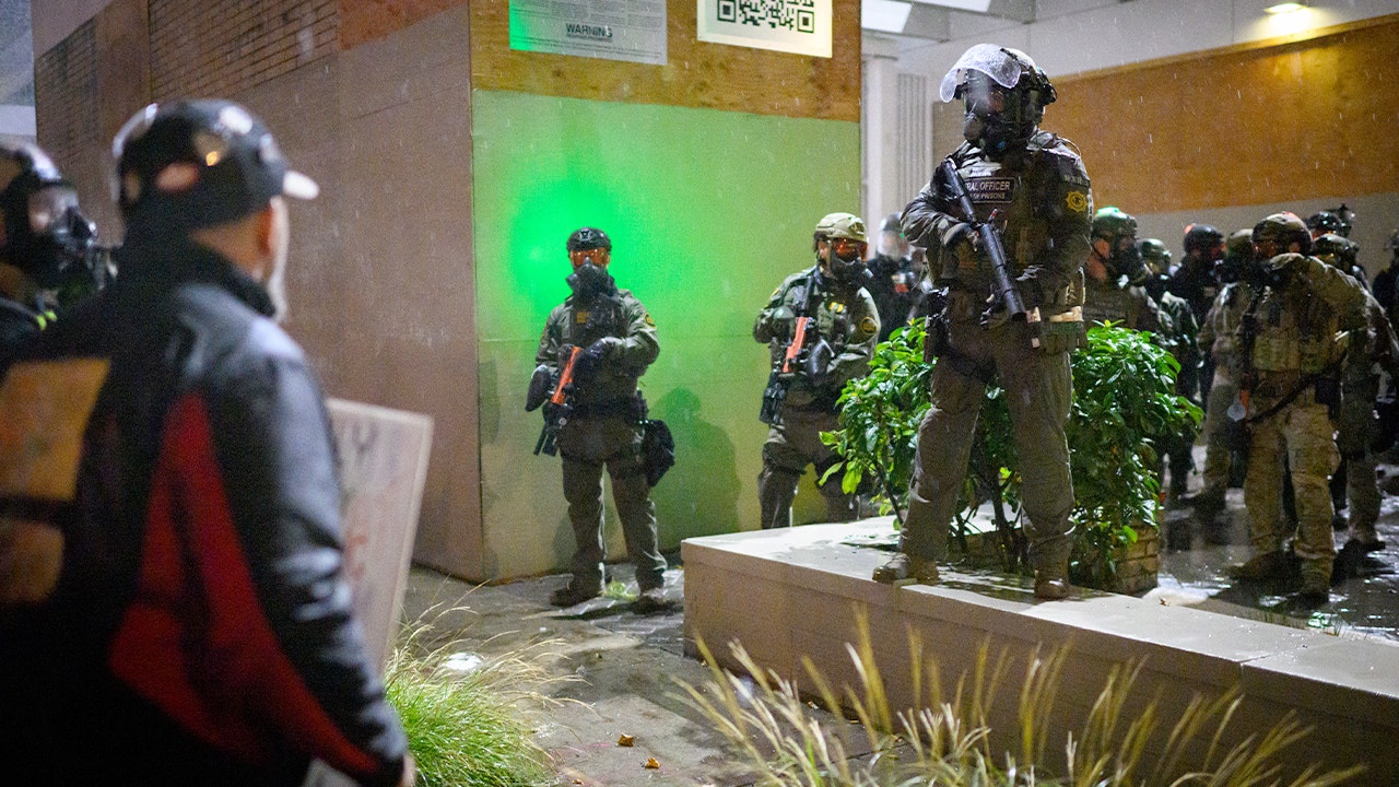 Demonstrators confront law enforcement outside a federal immigration facility during a nighttime protest in Portland.