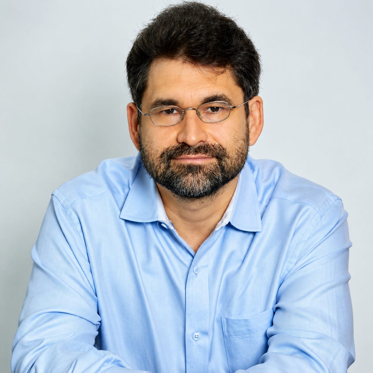 Mark Dinner poses for a portrait in a blue shirt