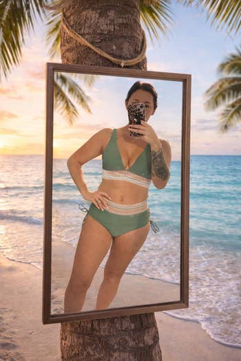 Person in green version of bikini takes a mirror selfie on a beach at sunset