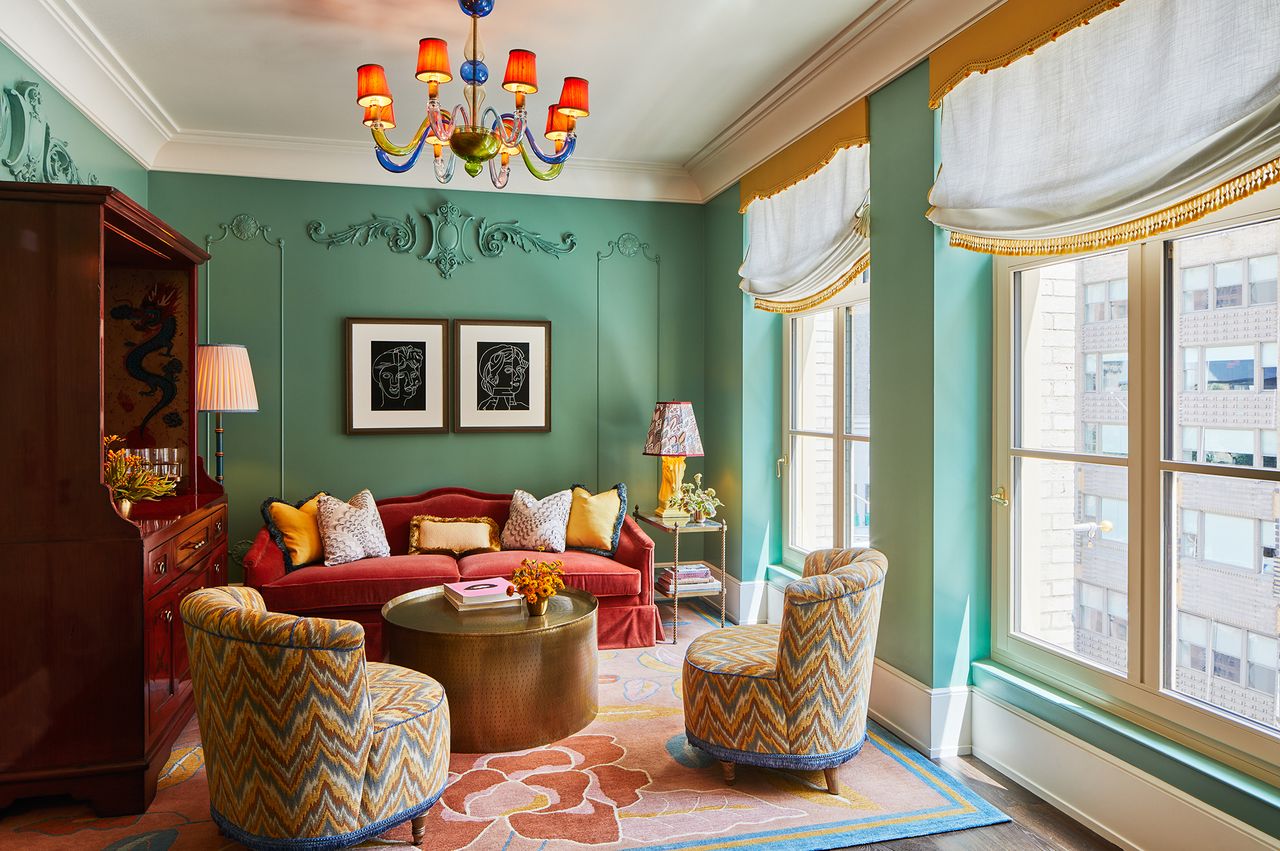 A luxurious living room with chairs a sofa and art on the walls located in a stylish hotel suite