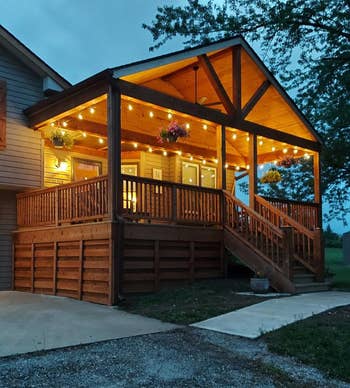 A cozy house porch with warm string lights hanging from the wooden roof, creating an inviting outdoor space