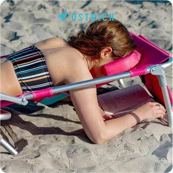 A model laying on their stomach with their face in the chair's cavity so they can read a book