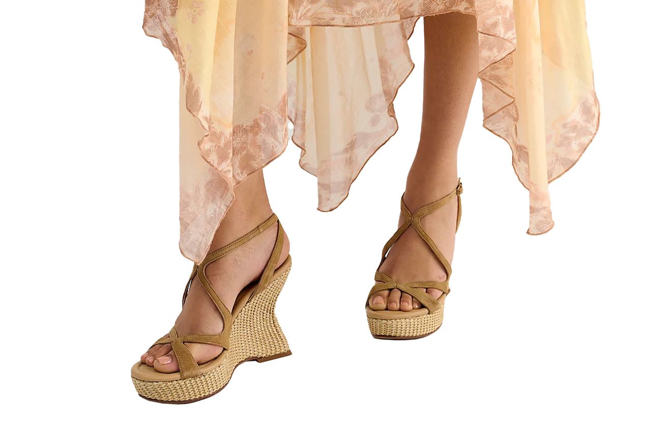 A closeup of a person wearing wedgeheeled sandals and a flowy skirt