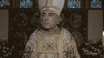 Person dressed in ornate religious attire, including a mitre and embroidered vestments, in a church setting