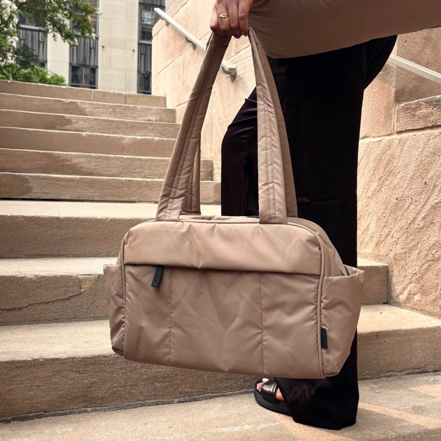Woman holding a small Luka duffel in left hand on a staircase. (Daaiyah James / NBC News)